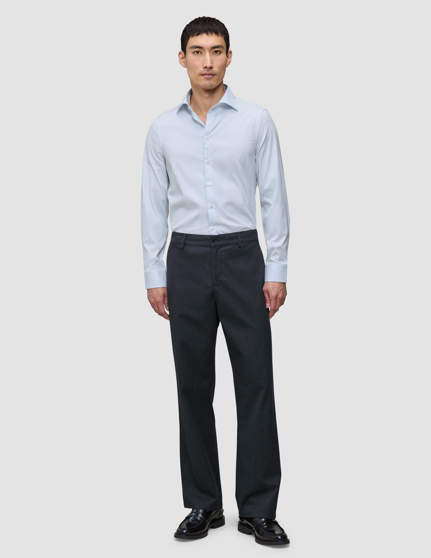 En mann kledd i en Elevated Shirt Regular Classic Blue Striped, mørke bukser og svarte loafers.
