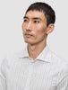 En mann kledd i en Elevated Shirt Regular Light Grey Striped, en elegant hvit skjorte med tynne, grå vertikale striper.