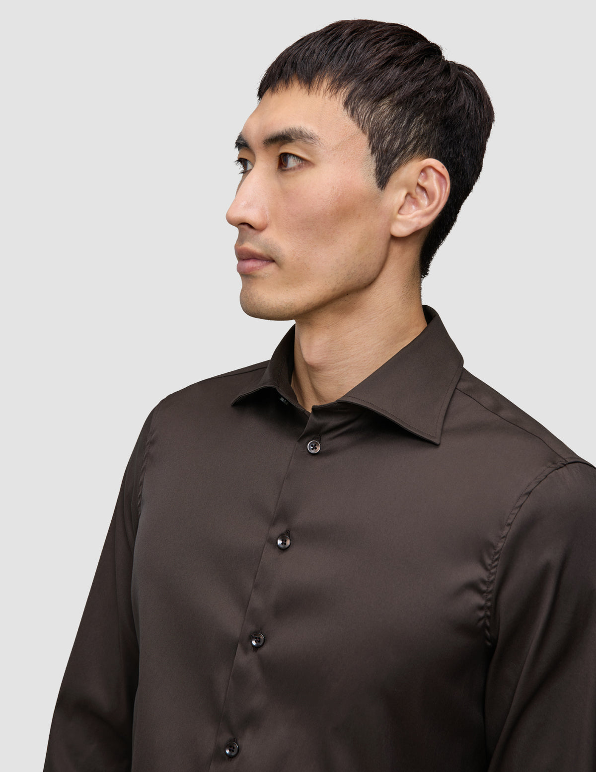 En mann kledd i en mørkebrun Elevated Shirt Slim Dark Brown-skjorte i Pima-bomull med smal passform og knapper.