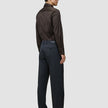 Bakfra-bilde av en mann som har på seg en mørkebrun Elevated Shirt Slim, stappet inn i mørkegrå bukser og mørke skinnsko.