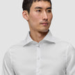 En mann iført en Elevated Shirt White Slim i Pima-bomull, med et hvitt design i smal passform og en spredt krage.