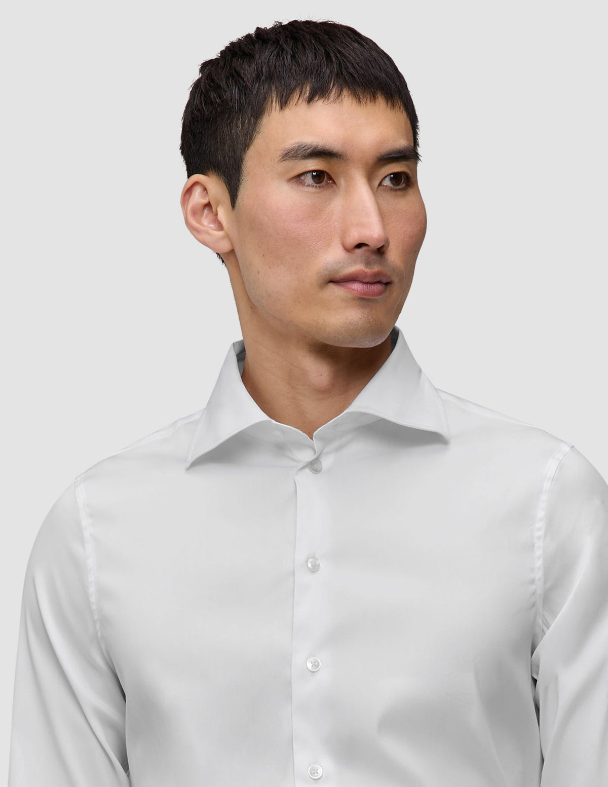 En mann iført en Elevated Shirt White Slim i Pima-bomull, med et hvitt design i smal passform og en spredt krage.