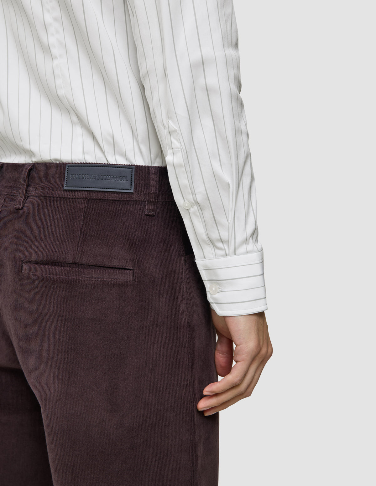En person som har på seg en Elevated Shirt Slim Light Grey Striped, som er stappet inn i mørkebrune corduroybukser.