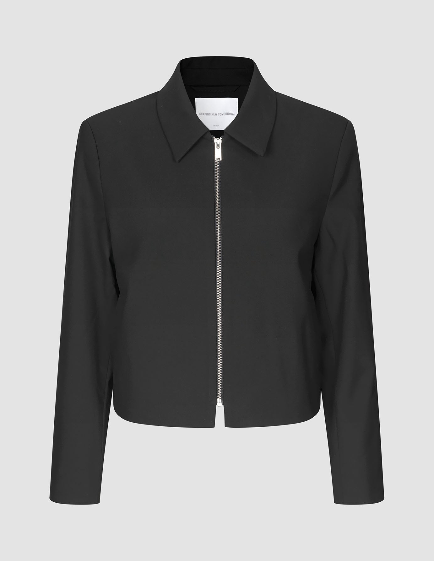 Essential Short Zip Jacket Black, en minimalistisk svart jakke med krage og en sølvfarget glidelås i full lengde foran.