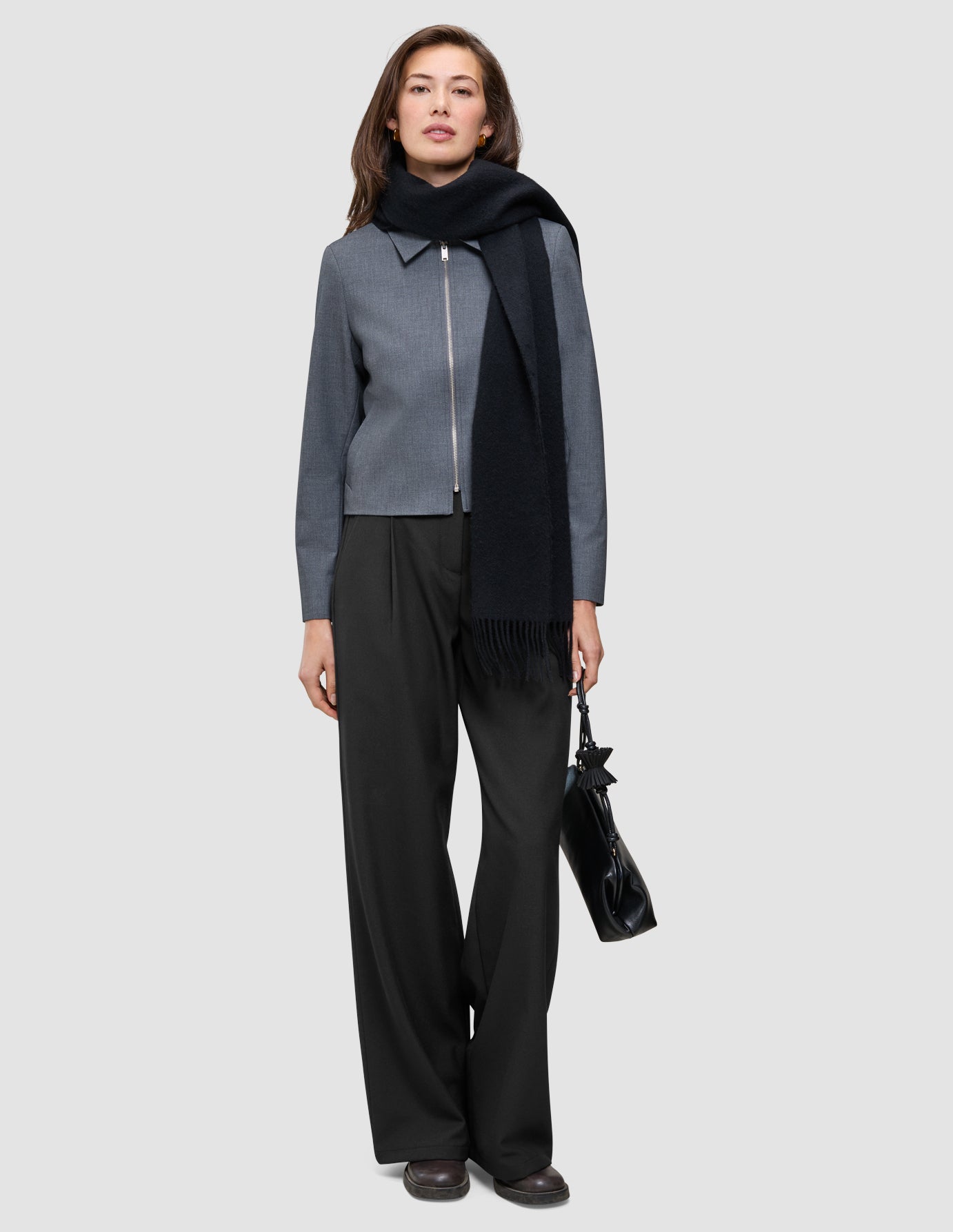 En modell har på seg en Essential Short Zip Jacket i mørkegrå melange, kombinert med et svart skjerf, bukser og en håndveske.