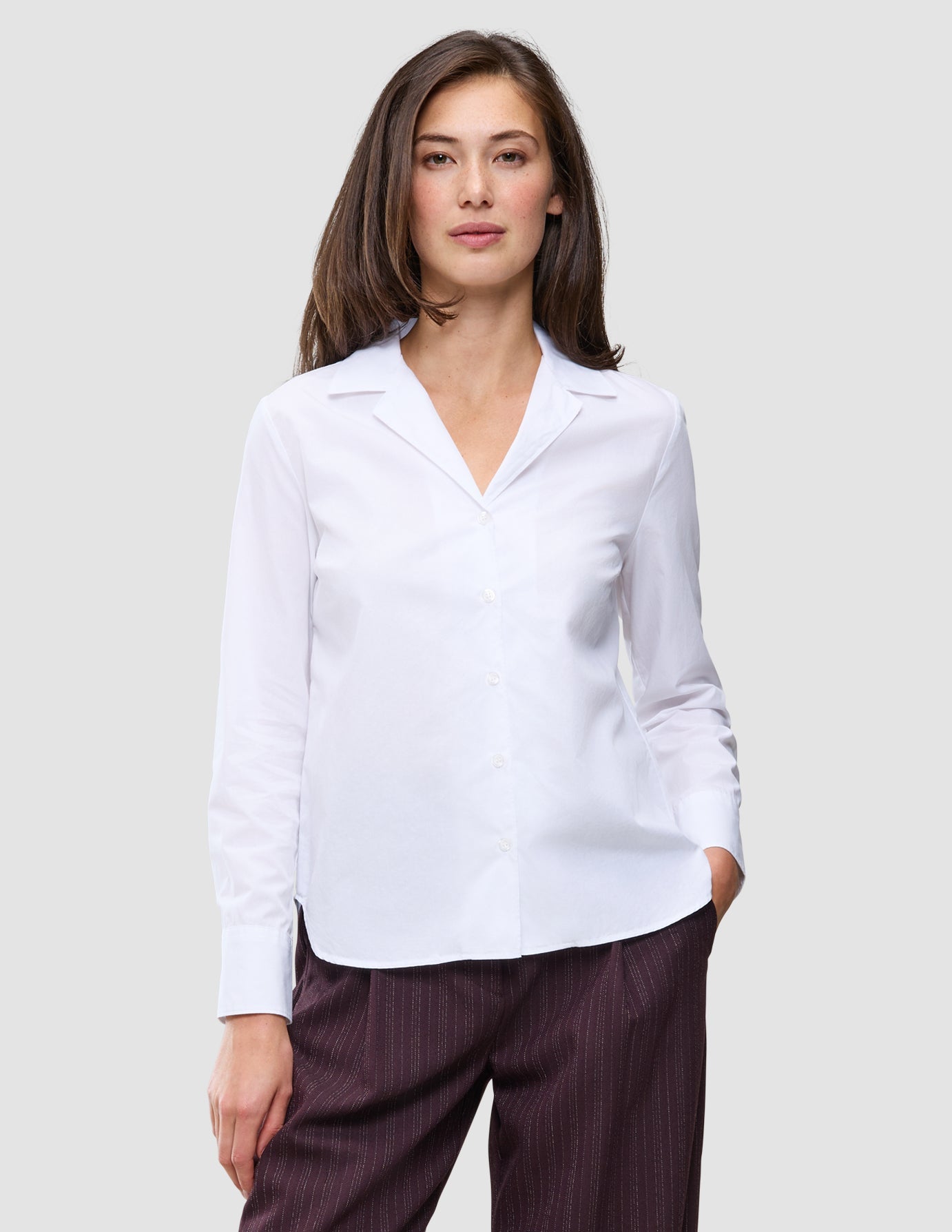 En kvinne iført en Madison Shirt White, en langermet skjorte med knapper og utskåret krage i Skandinavisk-design.