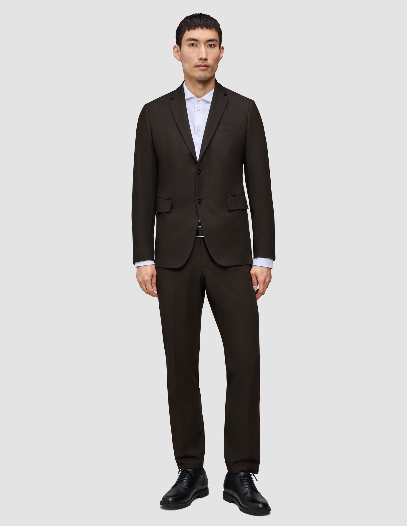 En mann kledd i en Motion Blazer Regular i fargen Cognac, hvit skjorte med krage og svarte dressko.