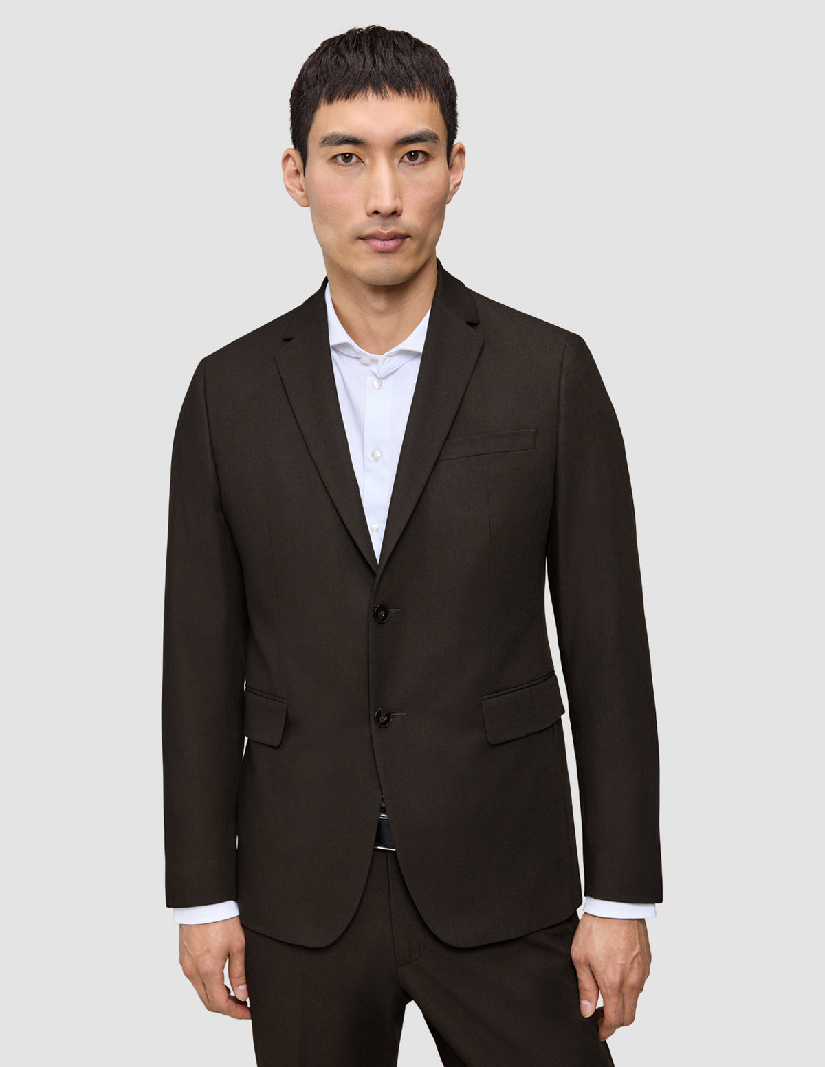 En mann kledd i en mørkebrun Motion Blazer Regular Cognac over en hvit skjorte med knapper.