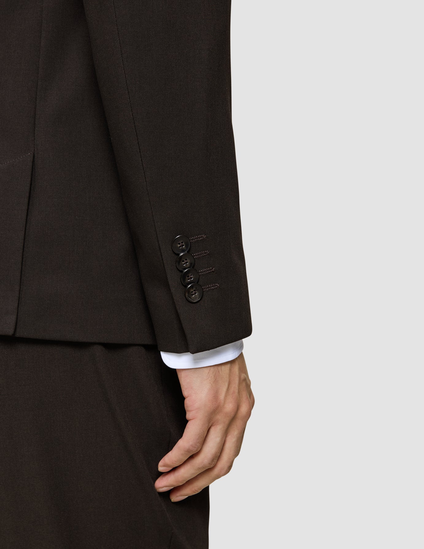 Nærbilde av en brun Motion Blazer Regular Cognac-erme med fire mansjettknapper og en hvit skjorteerme under.