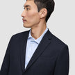 En mann i en Motion Blazer Regular i fargen Midnight Blue og en lyseblå stripete skjorte.