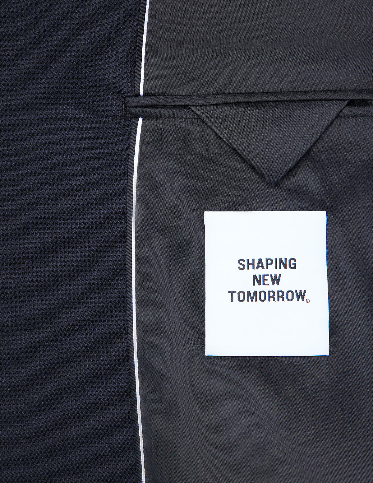 Interiøret i en mørkeblå Motion Blazer Regular Midnight Blue med et hvitt SHAPING NEW TOMORROW-merke.