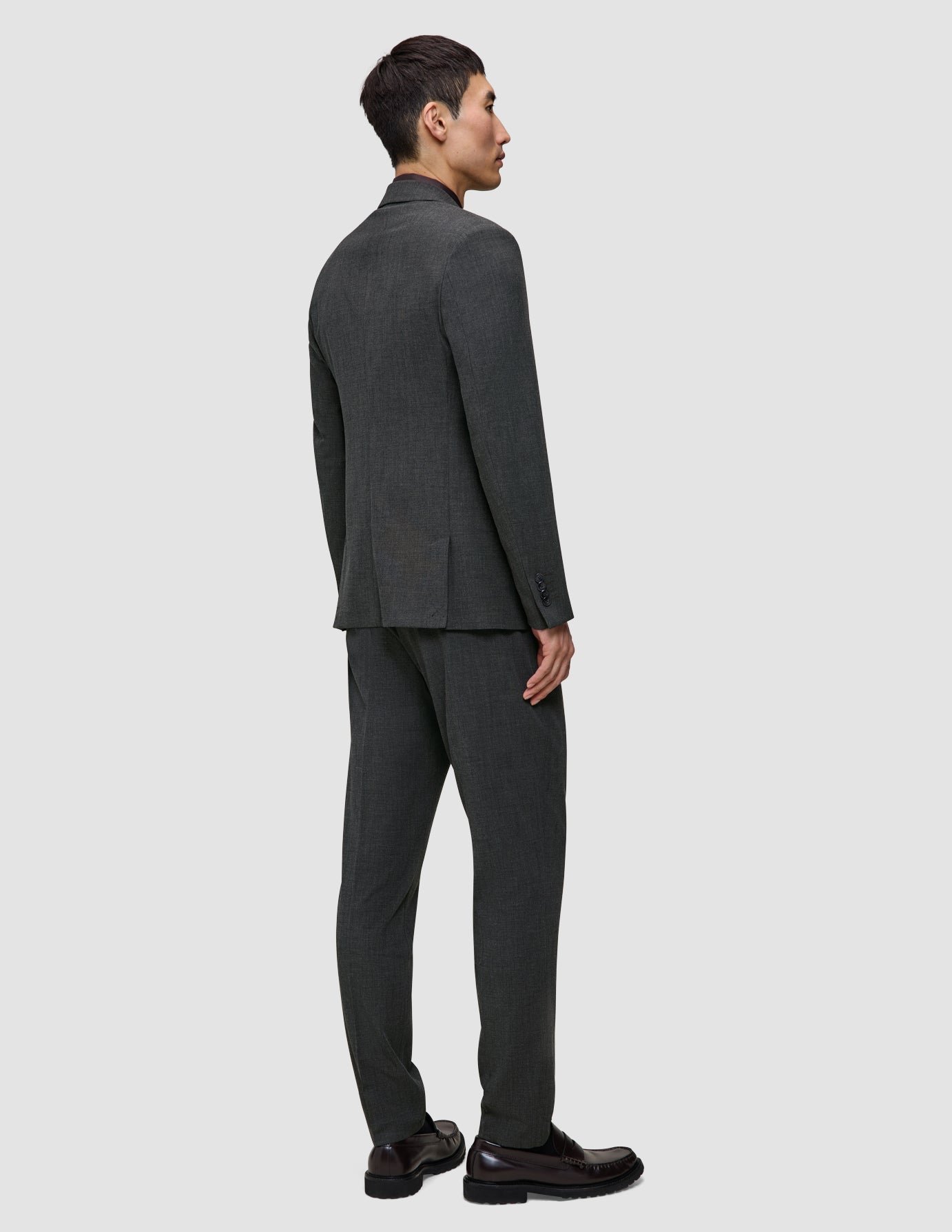En mann sett bakfra, kledd i en Motion Blazer Regular Pepper Grey-blazer og matchende bukser i pustende materiale.