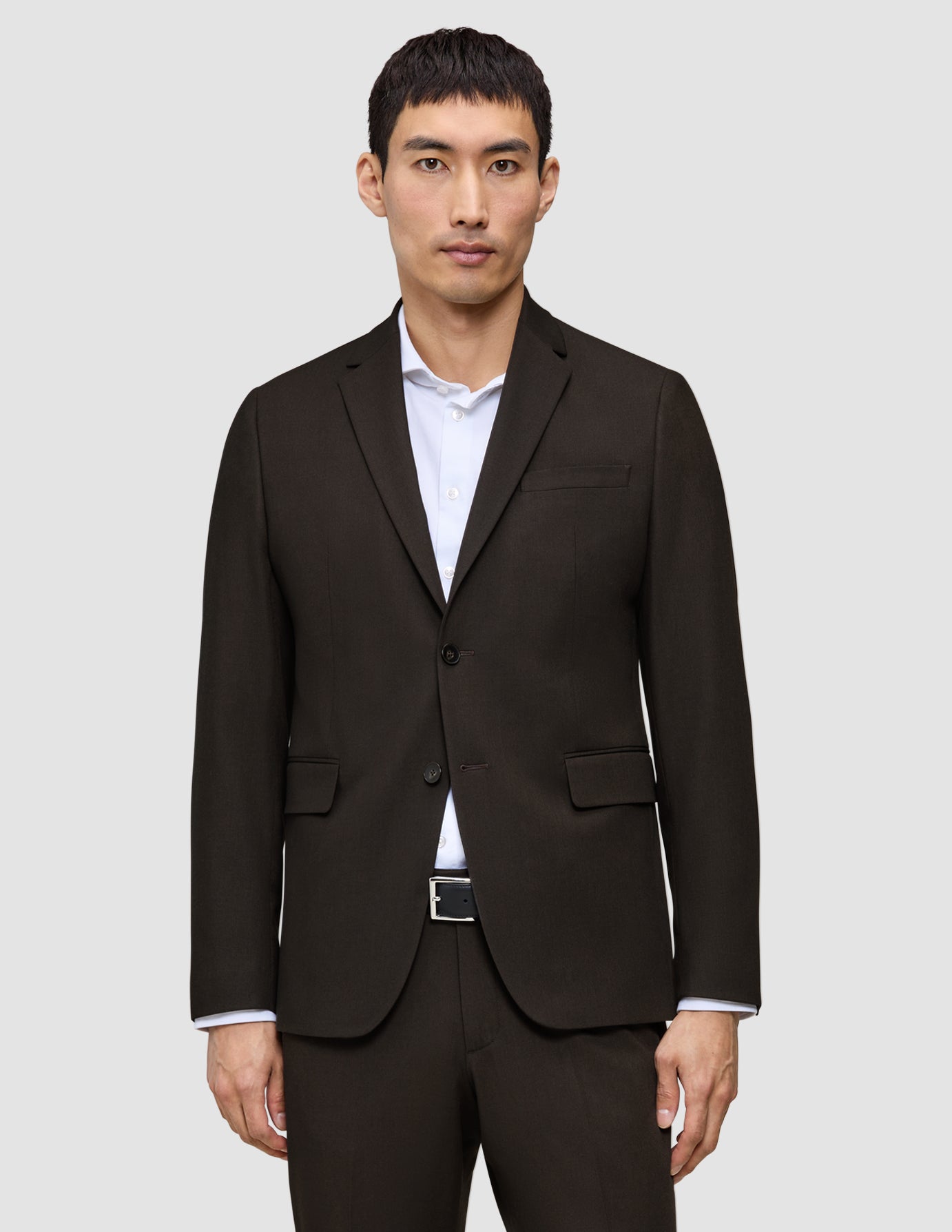 En mann som har på seg en mørkebrun Motion Blazer Slim Cognac over en hvit skjorte med knapper.