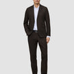 En mann kledd i en Motion Blazer Slim Cognac, hvit skjorte, svart belte og svarte dressko.