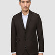 En mann som har på seg en mørkebrun Motion Blazer Slim Cognac over en hvit skjorte.