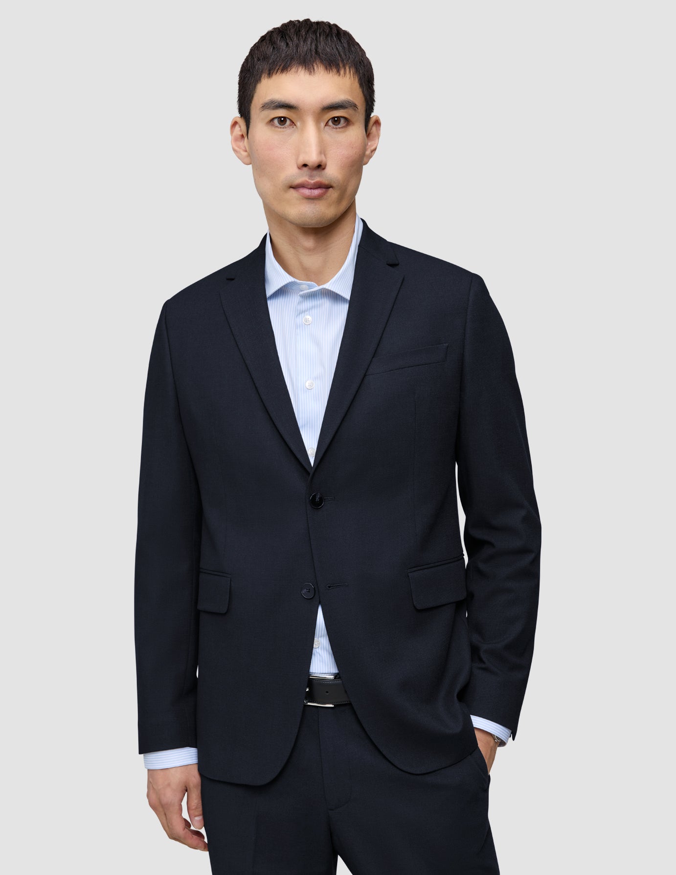 En mann har på seg en mørkeblå Motion Blazer Slim Midnight Blue over en lyseblå stripete skjorte med 360°-stretch.
