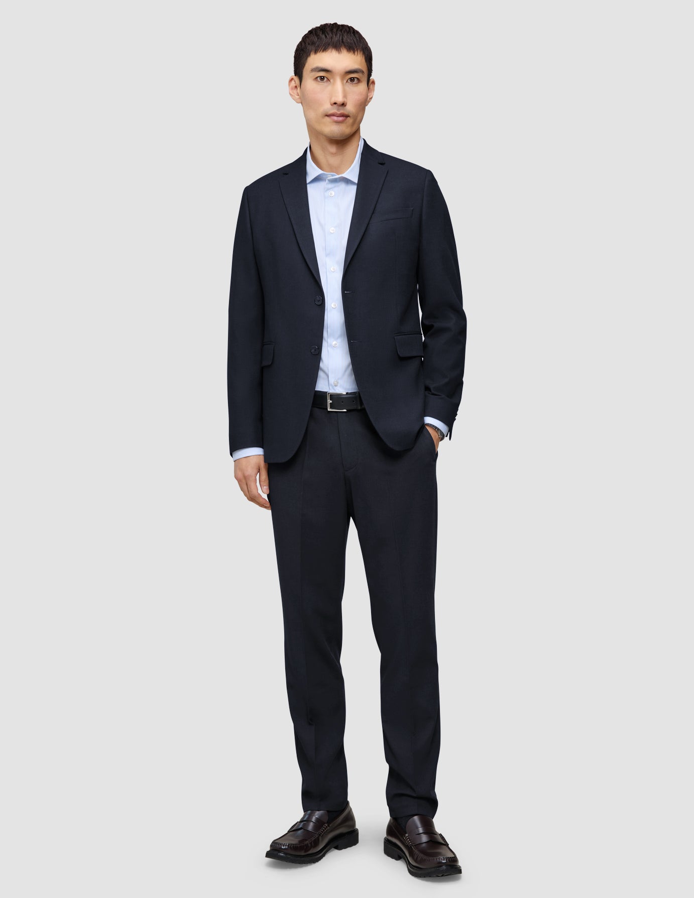 En mann kledd i en Motion Blazer Slim i fargen Midnight Blue, matchende bukser, en lyseblå skjorte og mørke loafers med 360°-stretch.