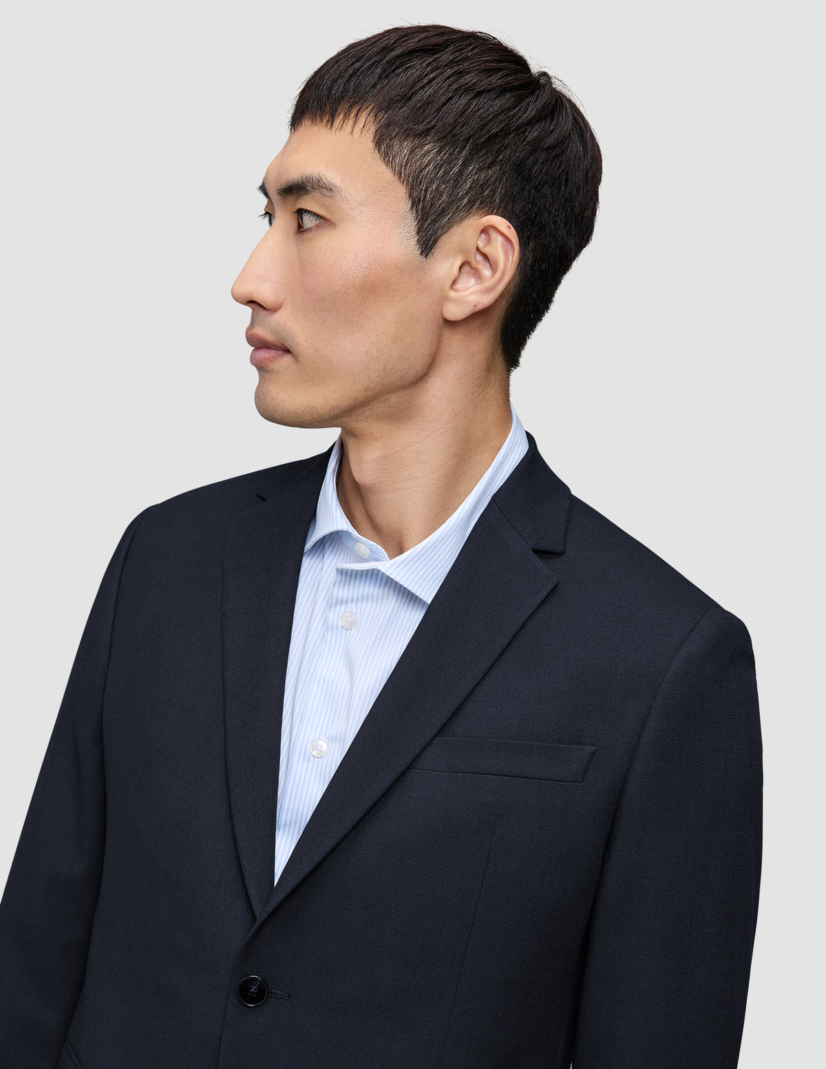 En mann sett i profil har på seg en mørkeblå Motion Blazer Slim Midnight Blue over en lyseblå stripete skjorte.