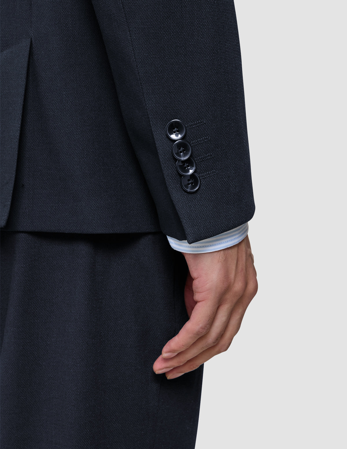 Nærbilde av en mørkeblå Motion Blazer Slim Midnight Blue-erme med fire mansjettknapper og en stripete skjorte under.