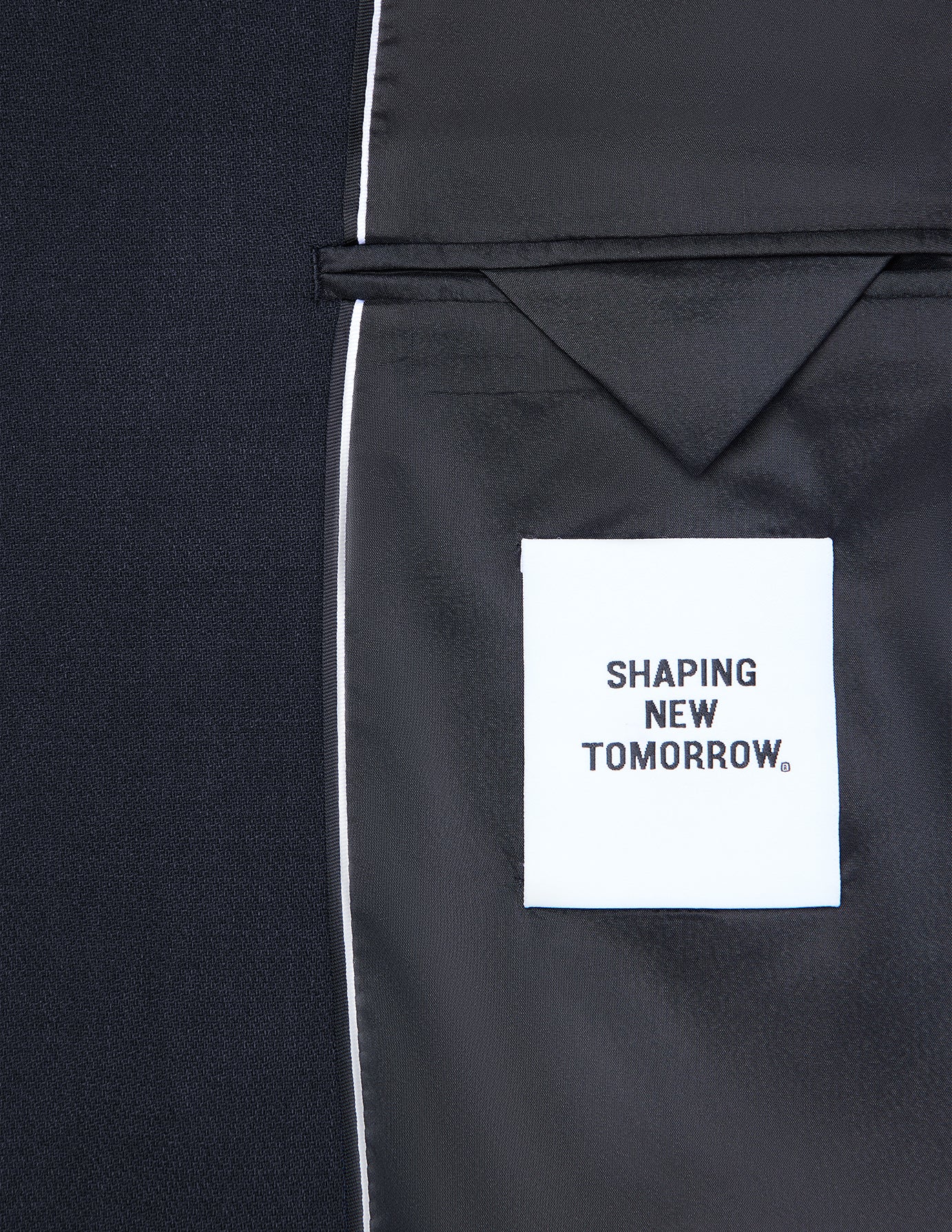 Interiøret i en mørkeblå Motion Blazer Slim Midnight Blue med en hvit SHAPING NEW TOMORROW-etikett.