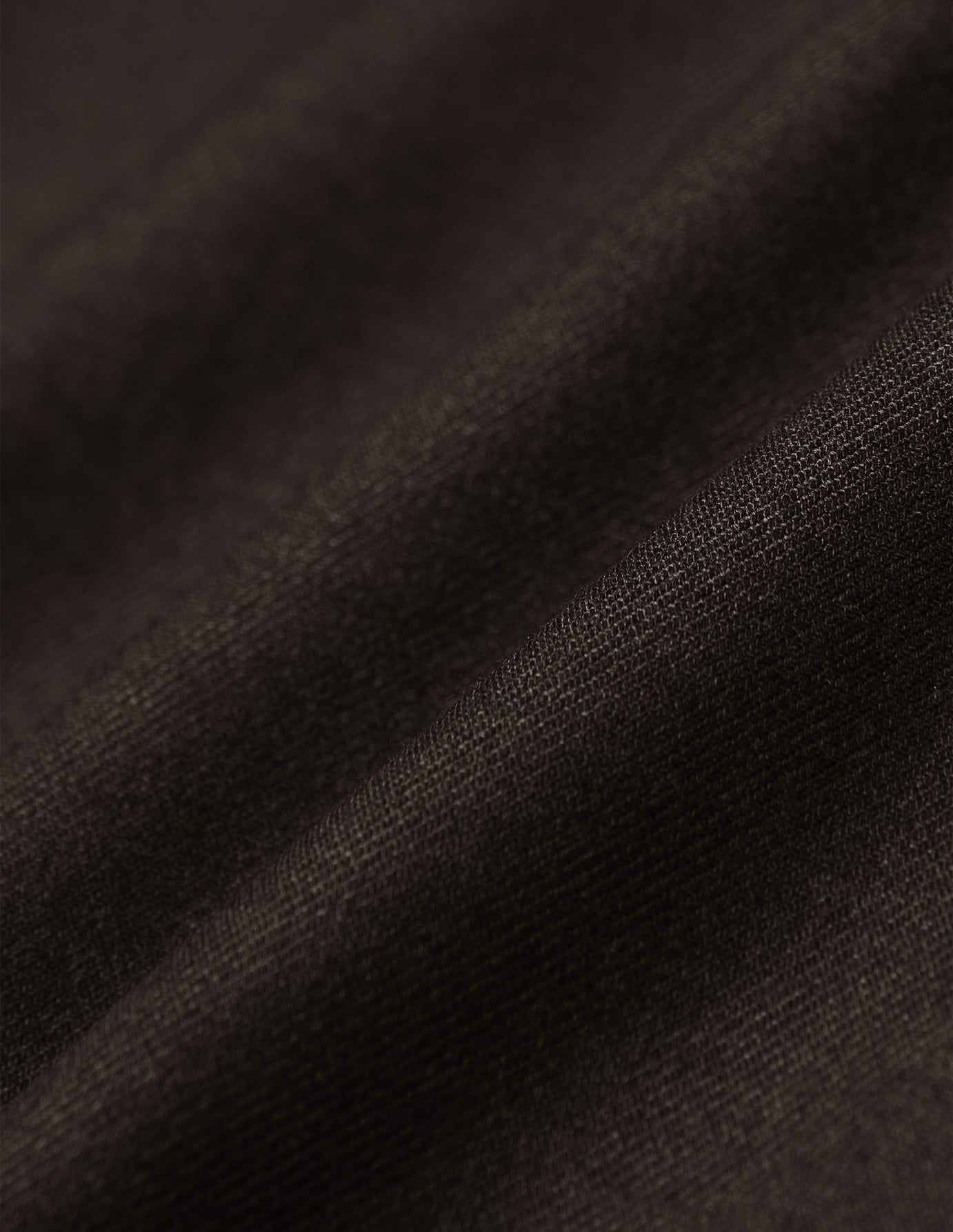 Nærbilde av myke folder i mørkebrunt 360°-stretchstoff på Motion Suit Pants Regular Cognac.