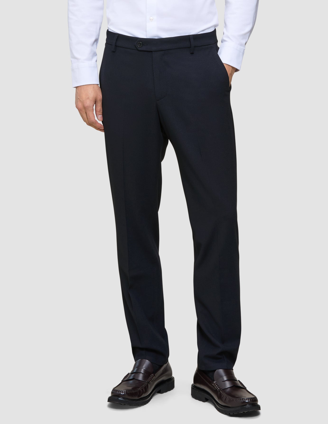 En person i en hvit skjorte, Motion Suit-bukser i vanlig passform i midnattsblått og mørkebrune skinnloafers.