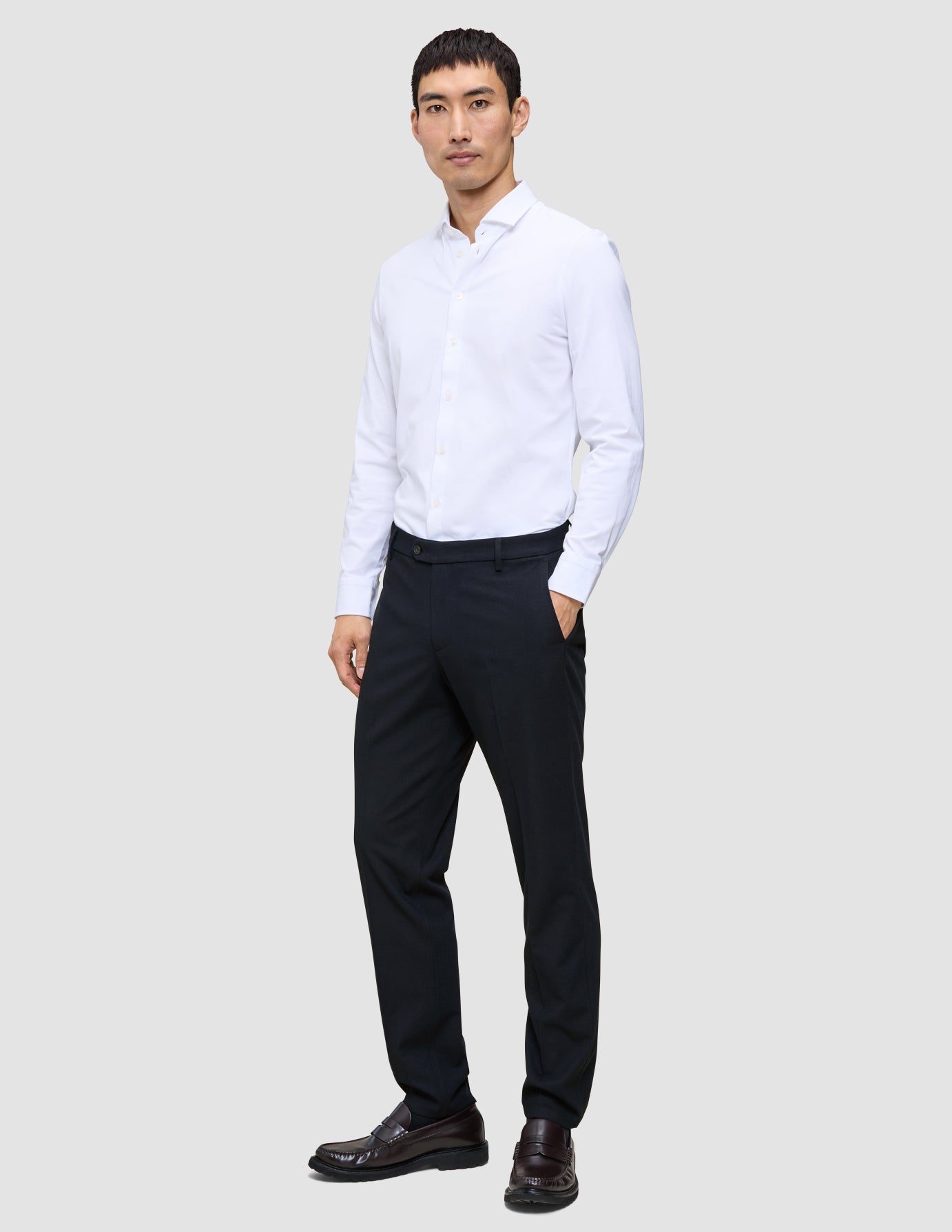 En mann kledd i en hvit skjorte med knapper og en midnattsblå Motion-dressbukse i vanlig passform.