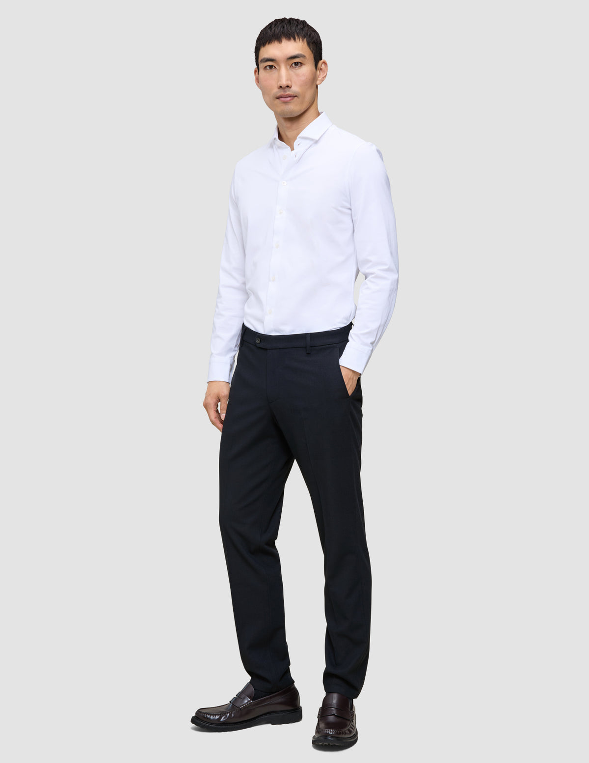 En mann kledd i en hvit skjorte med knapper og en midnattsblå Motion-dressbukse i vanlig passform.