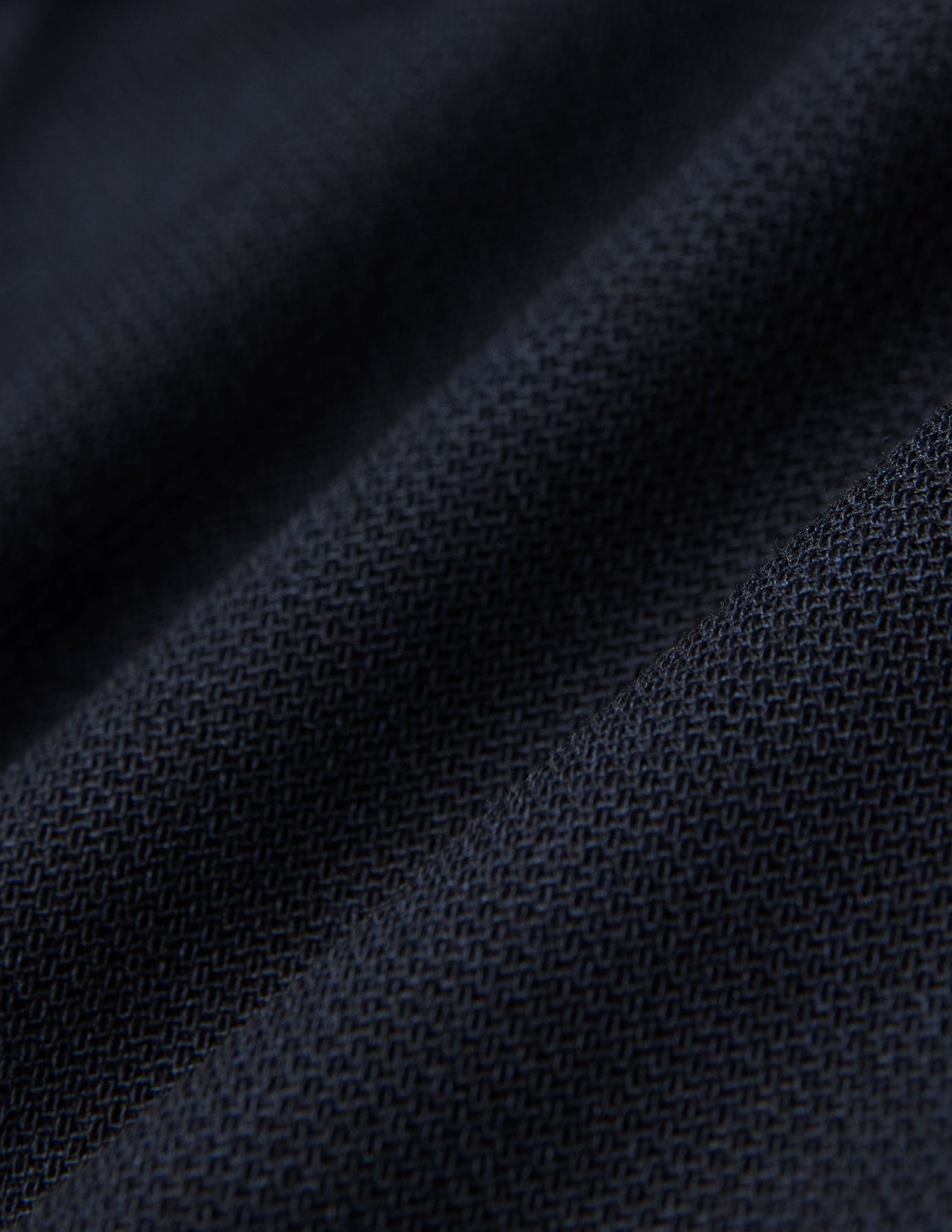 Nærbilde av brettede Motion Suit-bukser i Regular-modell, fargen Midnight Blue, med mørkeblått strukturert stoff og 360°-stretch.