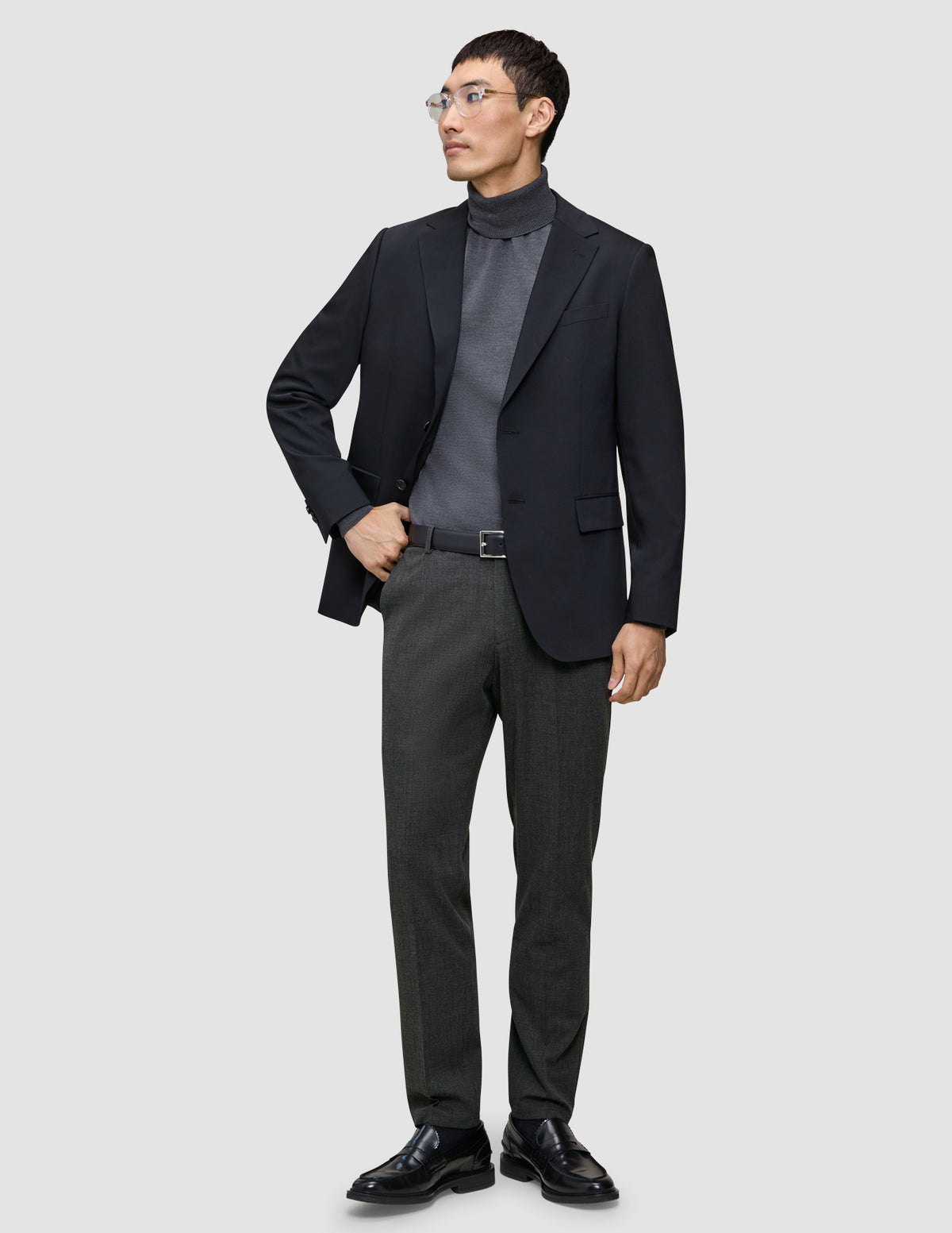 En mann i svart blazer og grå turtleneck har på seg Motion Suit Pants Regular Pepper Grey med skandinavisk design.