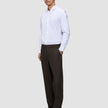 En mann i en hvit skjorte og Relaxed Cognac Motion-dressbukser med avslappet passform.
