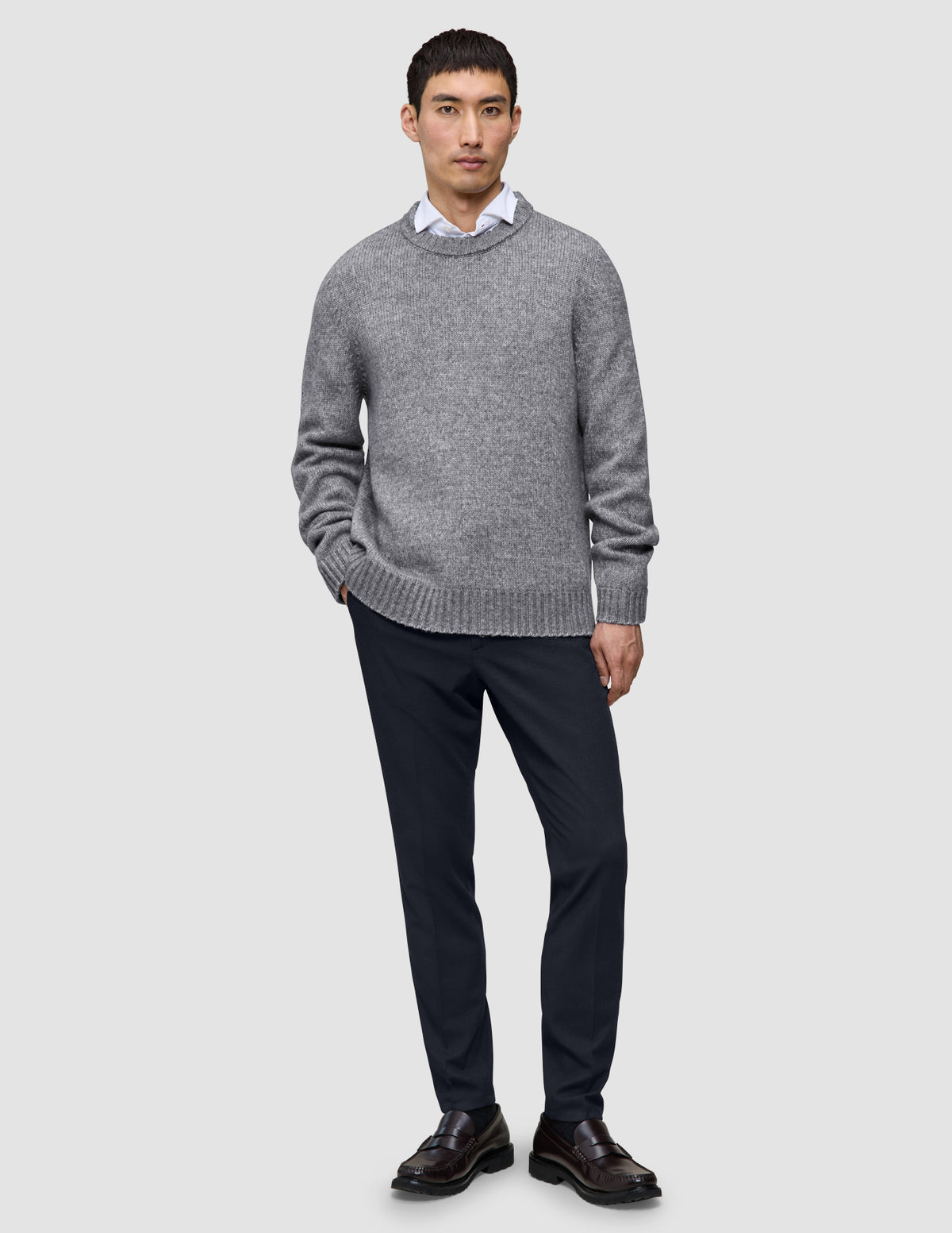 En mann i en grå genser, hvit skjorte med krage og Midnight Blue Motion Suit Pants Slim i skandinavisk design.