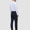 En mann sett bakfra, kledd i en hvit skjorte, Motion Suit Pants Slim i midnattsblått og mørke skinnloafers.