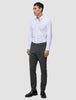 En mann i en hvit skjorte med knapper, Motion Suit-bukser i Slim-modell i fargen Pepper Grey og svarte dressko.