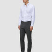 En mann i en hvit skjorte med knapper, Motion Suit-bukser i Slim-modell i fargen Pepper Grey og svarte dressko.