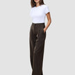 En person har på seg en hvit T-skjorte og Serene Pants Wide Walnut Herringbone – en buksemodell med høy midje, vide ben og nålestriper.