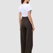 En kvinne sett bakfra, kledd i en hvit T-skjorte og Serene Pants Wide Walnut Herringbone med en diskret vertikal nålestripe.
