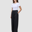 En kvinne kledd i en hvit T-skjorte og svarte Serene Pants Wide Black-bukser med høy midje og vide ben.