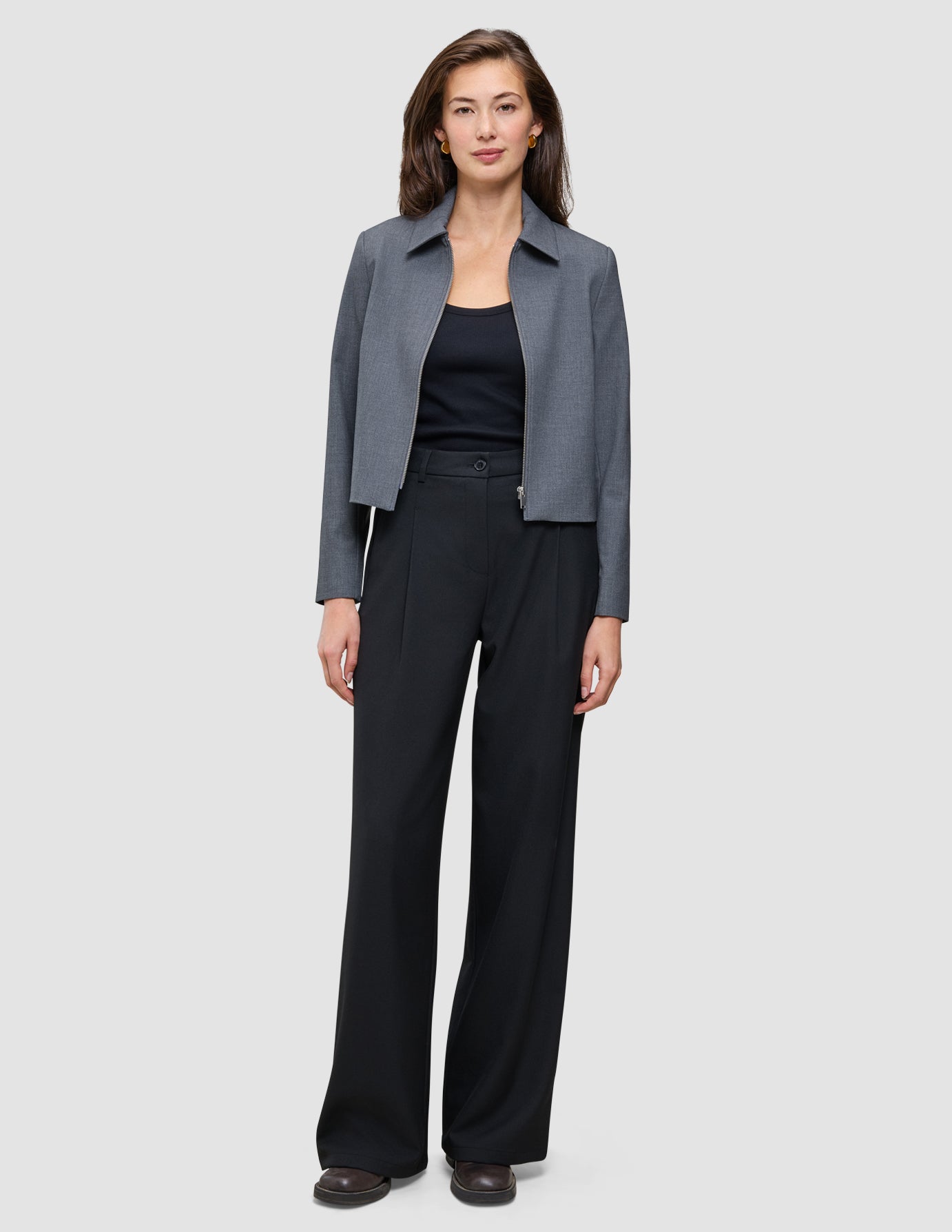En kvinne har på seg en grå, kort jakke, en svart tank-top og svarte Serene Pants Wide Black.