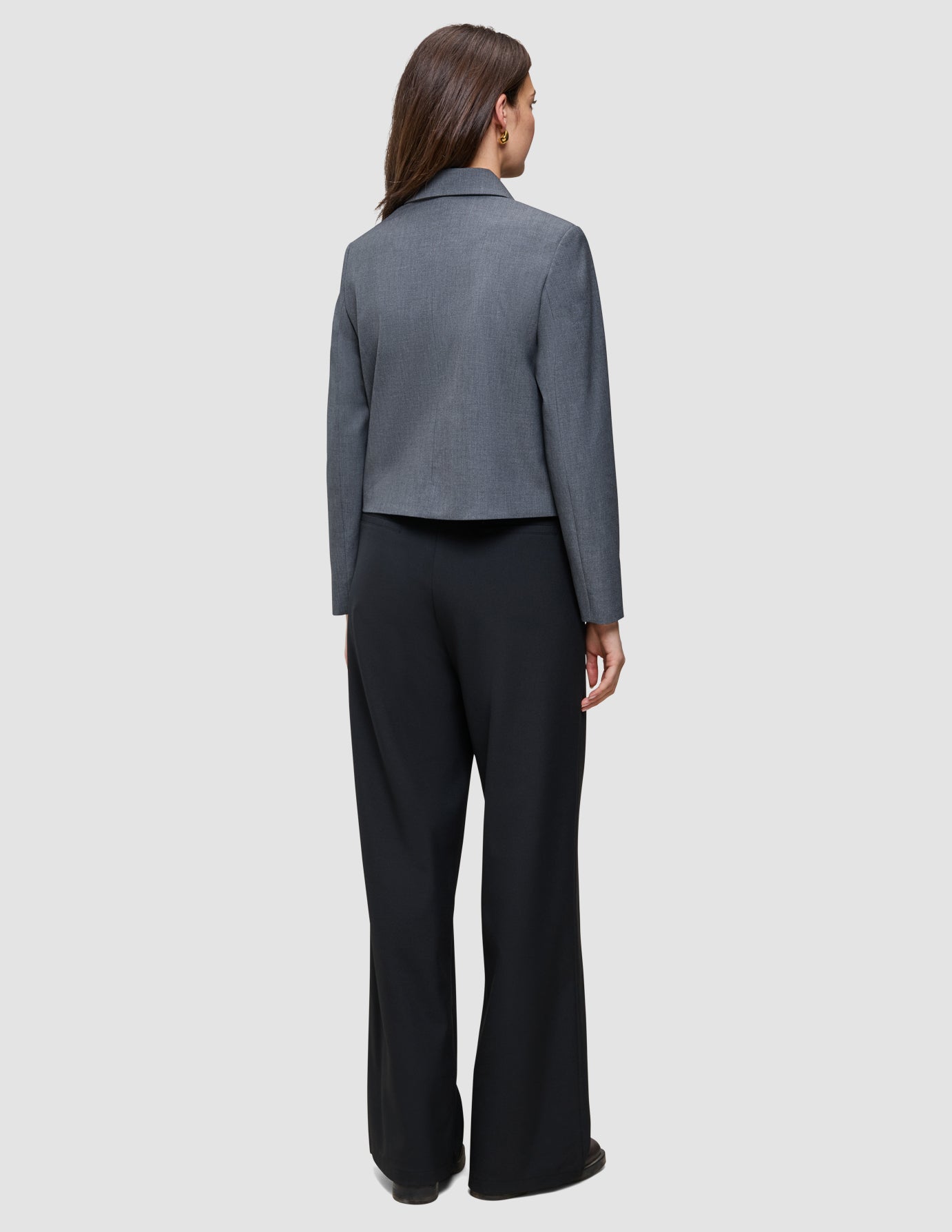 En person sett bakfra, kledd i en grå blazer og svarte Serene Pants Wide Black.