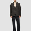 En mann har på seg en Timeless Wool Blazer Slim i mørkebrun rutemønster over en beige turtleneck og mørke bukser.