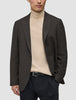 En person har på seg en Timeless Wool Blazer Slim i mørkebrun rutemønster over en beige turtleneck og svarte bukser.