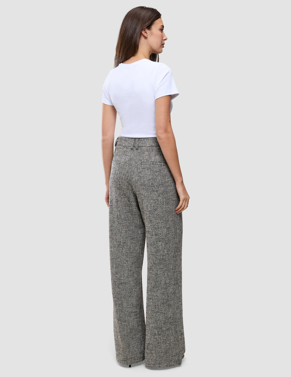 En kvinne sett bakfra, kledd i en hvit T-skjorte og grå Women Ashryn Pants Wide Domino Herringbone-bukser med vide ben.