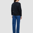 Sett bakfra har personen på seg en svart, tykk og myk ullstrikket cardigan for kvinner over en hvit skjorte og blå jeans.