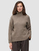 En kvinne iført en taupefarget, grovstrikket turtleneck i myk ull for kvinner, i fargen Taupe Melange.