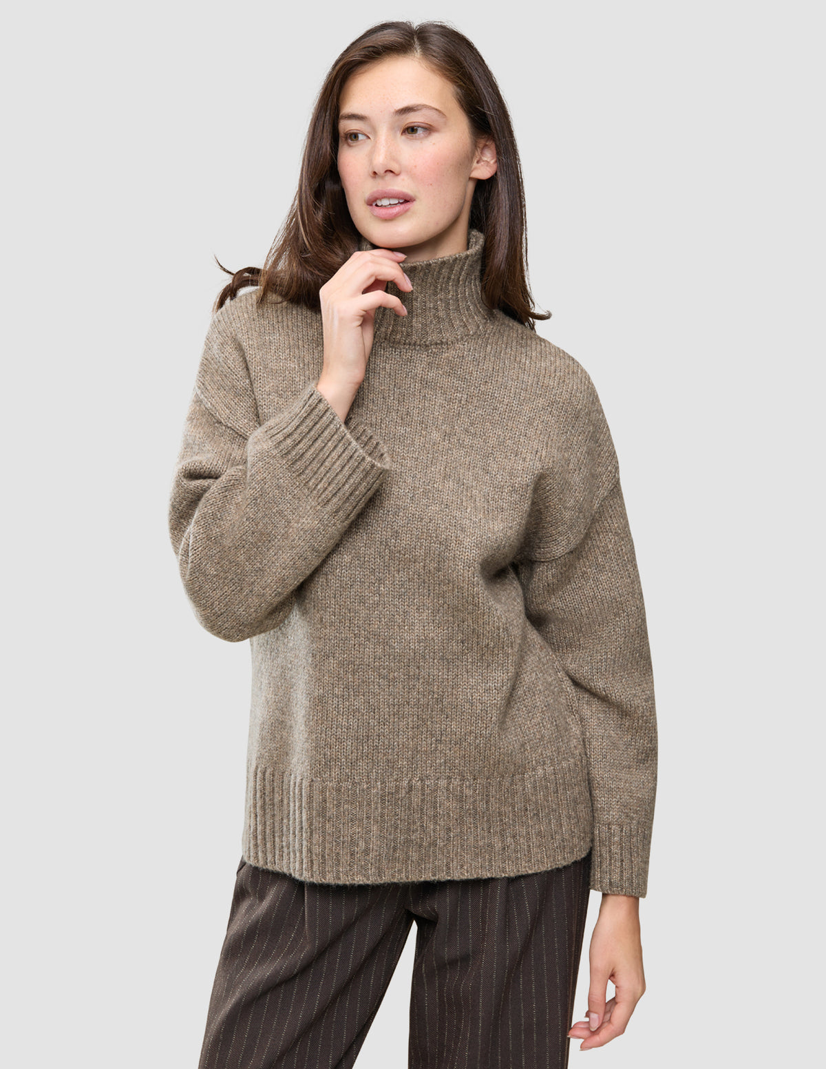 En kvinne som har på seg en Women Chunky Soft Wool Knit Turtleneck Taupe Melange-genser.
