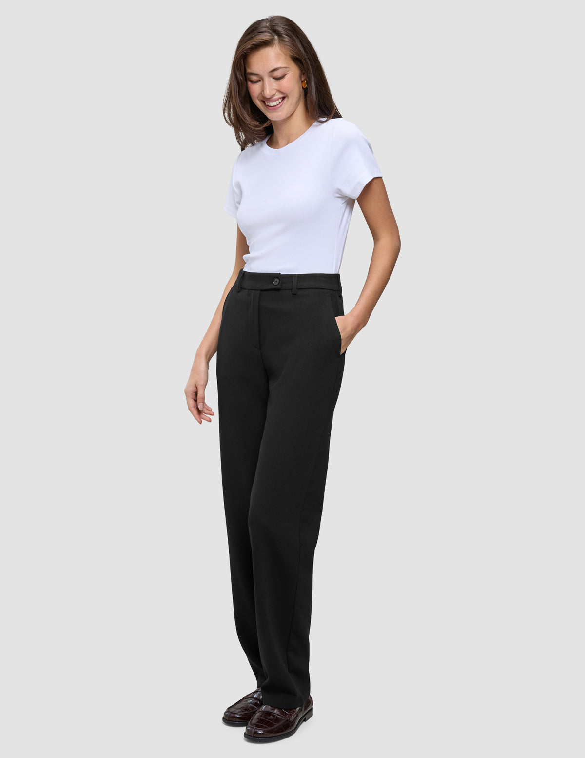 En kvinne iført en hvit T-skjorte og Women GO2 Pants Straight Black i klassisk skandinavisk design.