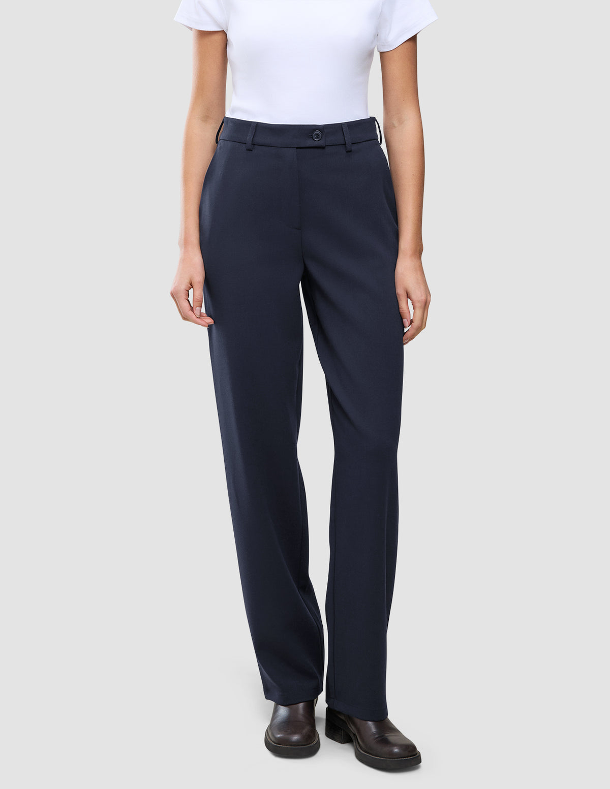 En person som har på seg en hvit T-skjorte stappet ned i Women GO2 Pants Straight Blue Nights og mørke skinnsko.