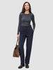 En kvinne i en grå topp med lange ermer og Women GO2-bukser i modell Straight Blue Nights, som holder en brun bæreveske.