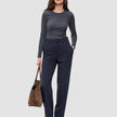 En kvinne i en grå topp med lange ermer og Women GO2-bukser i modell Straight Blue Nights, som holder en brun bæreveske.